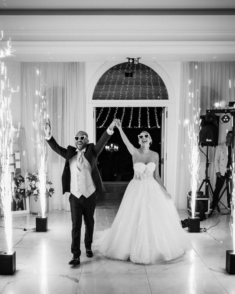 Manlio e Consuelo entrano alla festa tra le fontane luminose